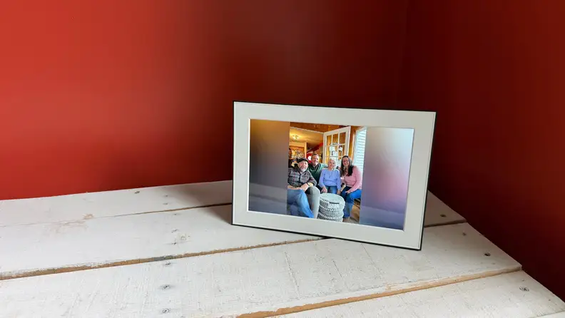 A digital frame stands on a white table