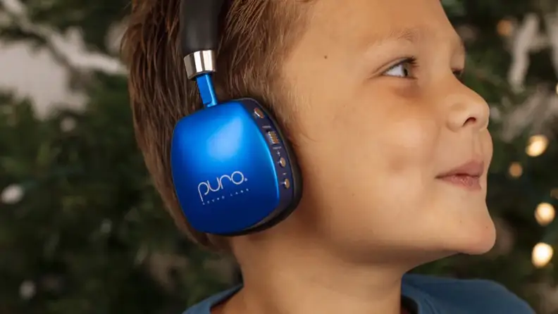 Child wearing blue PuroQuiet Plus headphones.