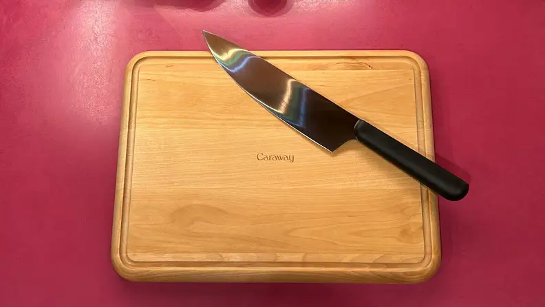 The cutting board with a chef's knife on it.