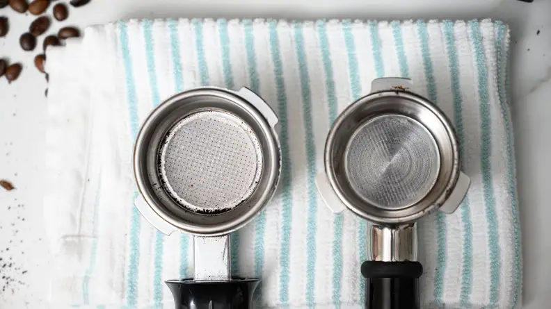 Two portafilters on a striped kitchen towel, shot from above.