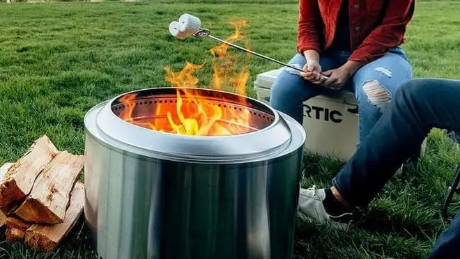Two people make s'mores on a Solo Stove outside.