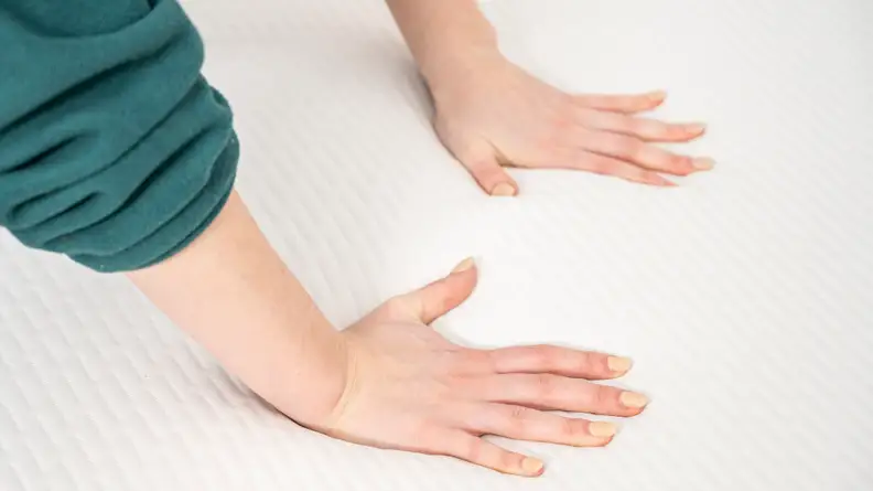 a woman's hands press into the surface of the Tuft & Needle Original