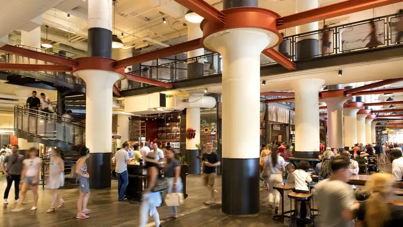 Bustling food hall interior with columns and a spiral staircase