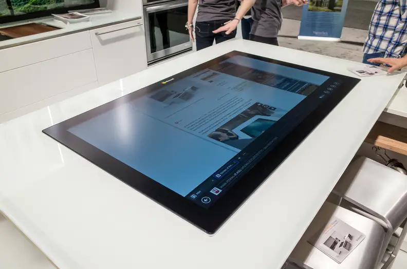The "social table" is defined by a gigantic Windows 8 tablet screen, which can be used to cast webpages and videos to the backsplash displays.