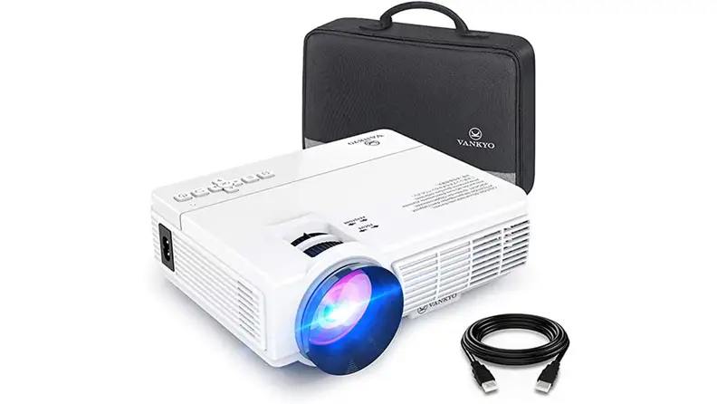 The Vankyo Leisure 3 mini projector, a small white box with built-in controls and a large lens on one side, sits beside a leather carrying case.