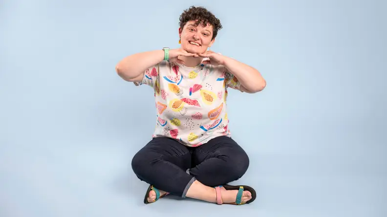Person sitting on the floor crosslegged smiling at camera