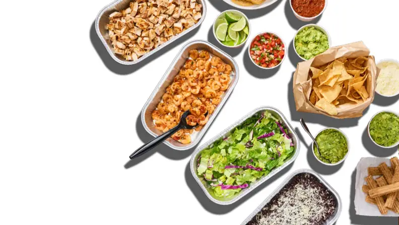 An overhead spread of taco fillings, including shrimp, chicken, salad, and chips