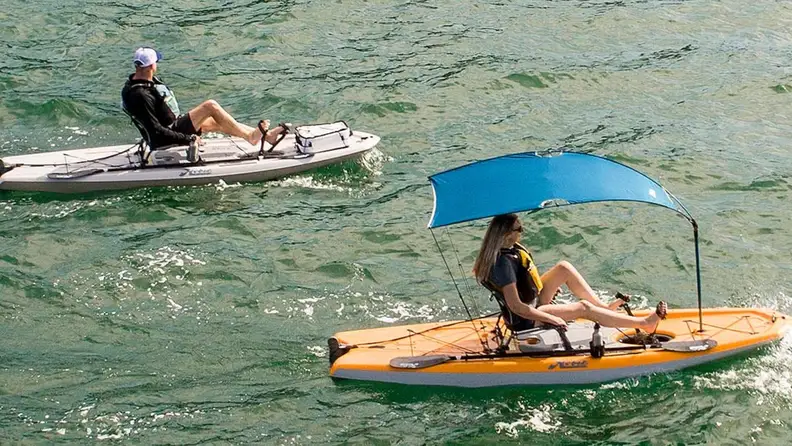 Two Lynx pedal kayaks on the water. One has a blue sunshade attached,