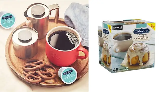 On left, coffee in red mug sitting next to chocolate covered pretzels, creamers and Cinnabon K-cups. On left box of Cinnabon K-cups