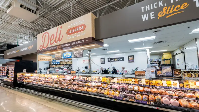 H-E-B deli case with sliced meats under a "Deli" sign