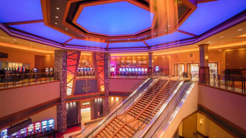 Interior of Yaamava’ Resort & Casino at San Manuel featuring grand escalators, colorful lighting, and a spacious gaming floor.