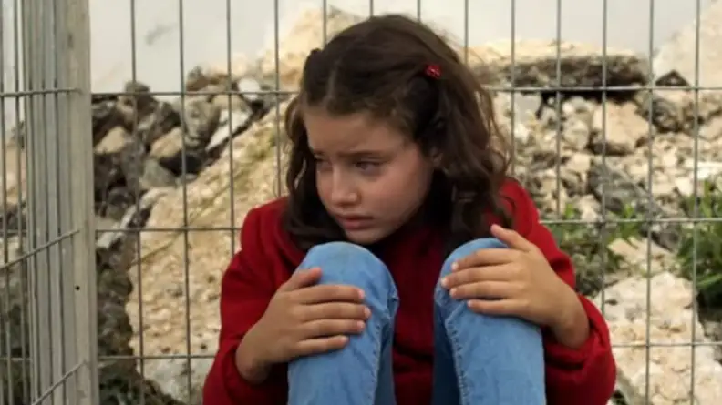 A still from the short film "The Present" featuring a young girl hugging her knees.