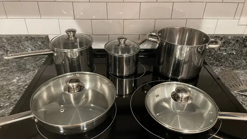 Stainless steel pots and pans sitting on an electric stovetop.