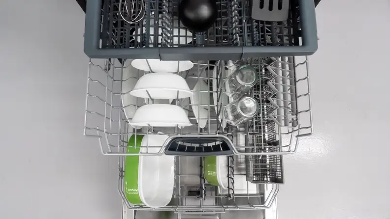 A top-down shot of the Bosch 500 Series SHPM65Z55N dishwasher, its door open and all three of its racks pulled out in a cascading fashion. Each rack is stocked with dishes.