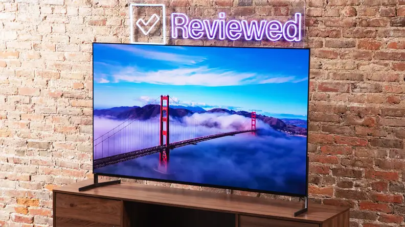 The Sony A95L QD-OLED TV positioned in front of a brick wall displaying a high-resolution image of the Golden Gate Bridge amidst heavy cloud cover