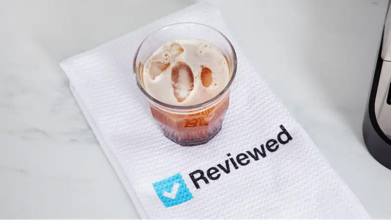 A cup of coffee on top of a napkin with the Reviewed logo.