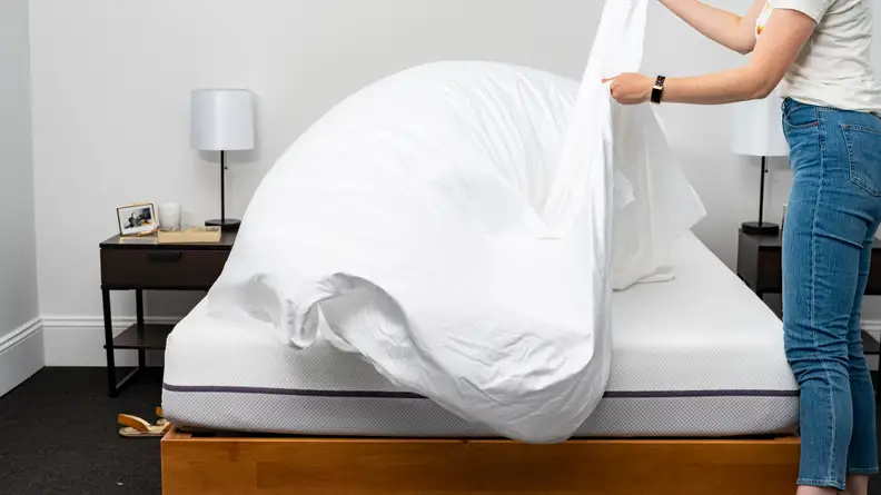 woman spreads a sheet over the Purple Mattress