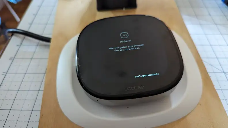 The Ecobee Smart Thermostat Premium is shown mounted on its trim plate with set-up instructions on its screen.
