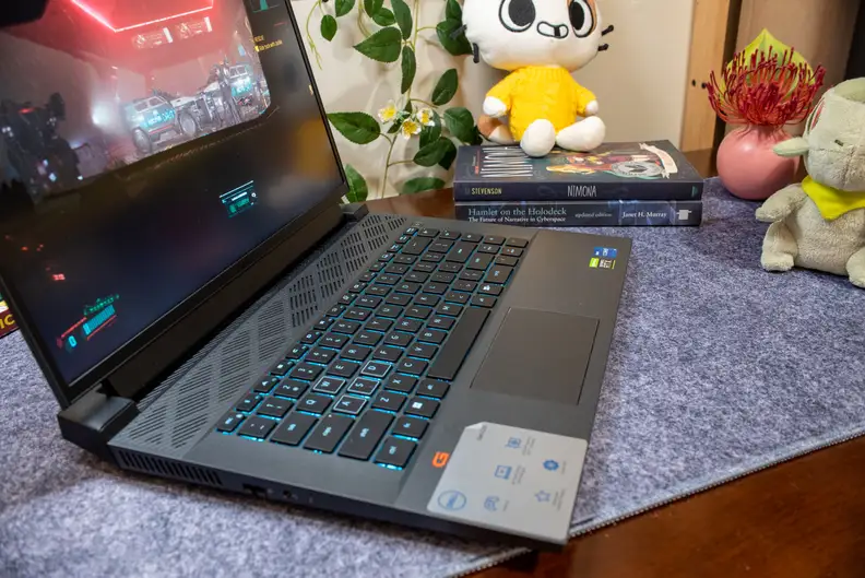 A three-quarter view of an open and powered on black laptop with a blue-lighted keyboard.