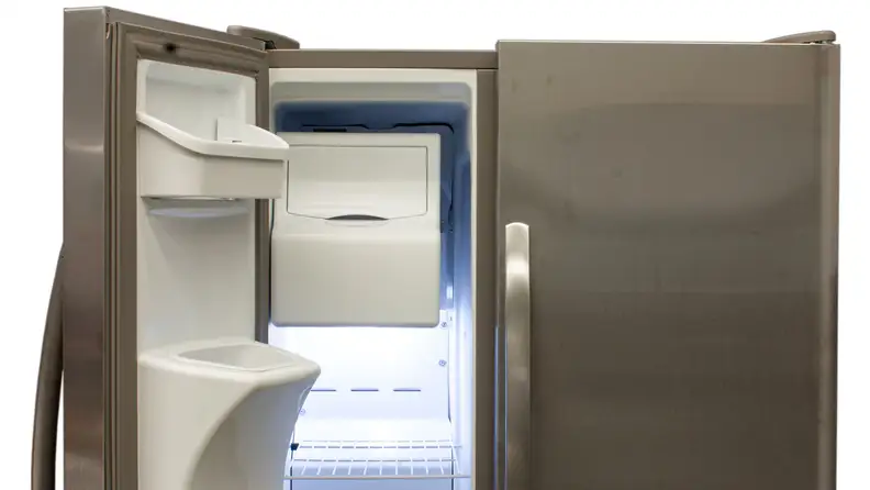 The top half of the Frigidaire FFSS2615TS side-by-side refrigerator, with the freezer door open to reveal its ice maker, racks, and storage bins built into the door's moulding.
