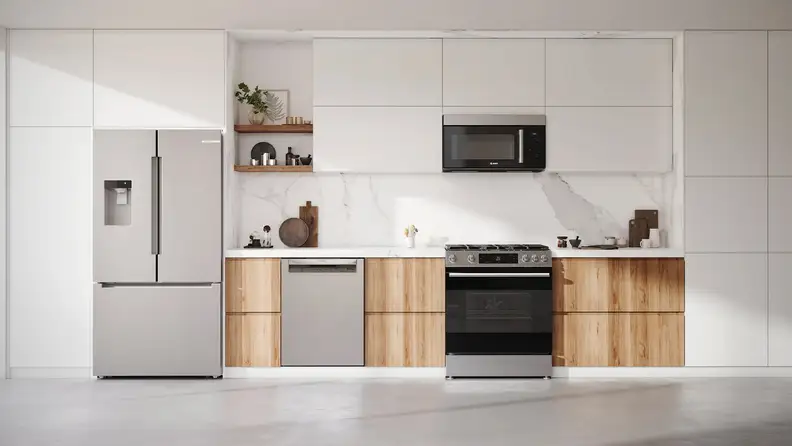Minimalist kitchen with white cabinets, wood accents, and stainless steel refrigerator, oven, and microwave.
