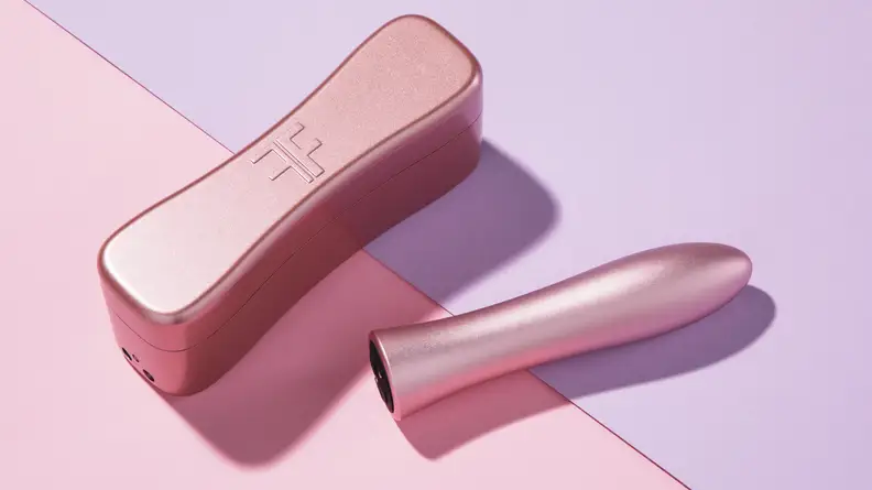 A pink Bougie Bullet vibrator next to its hardshell travel case on top of a pink and purple background.