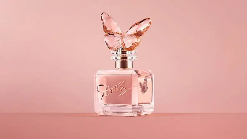 A butterfly-shaped perfume bottle against a pink background.