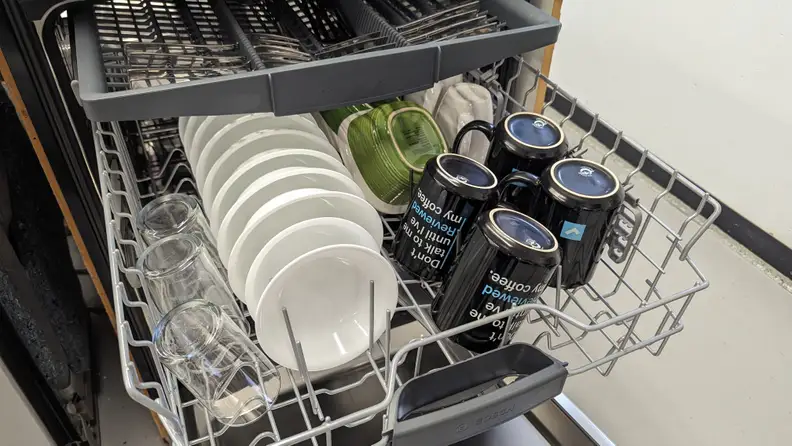 A close-up of the middle and third racks. The middle rack is full of small bowls, mugs, and cups, while the third rack is filled with neat rows of utensils.