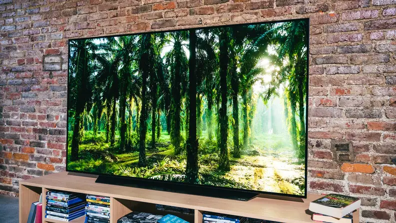 Flat screen smart TV playing movie in front of brick wall indoors.