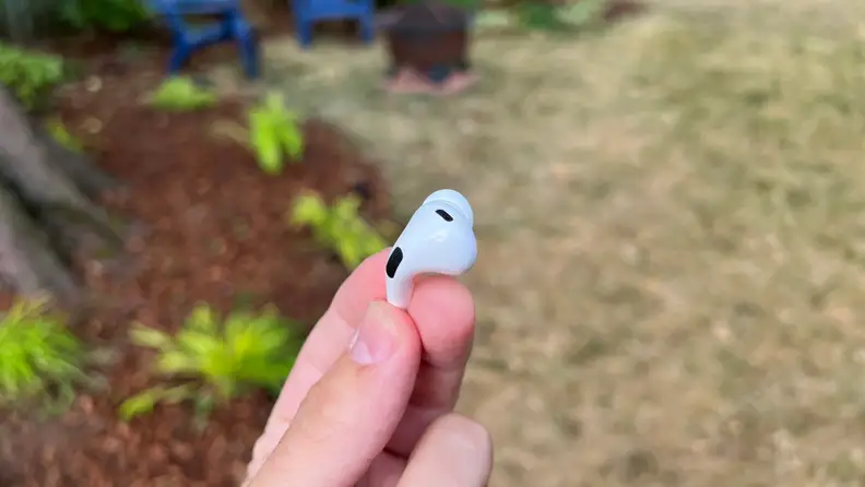 A close-up of a hand holding a single earbud of the Apple AirPods Pro (second gen).