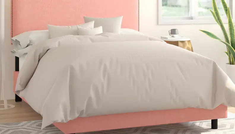 Bed with nude comforter and coral pink headboard