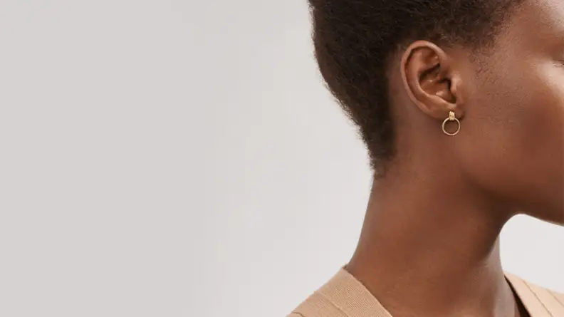 A woman wearing small gold hoop earrings