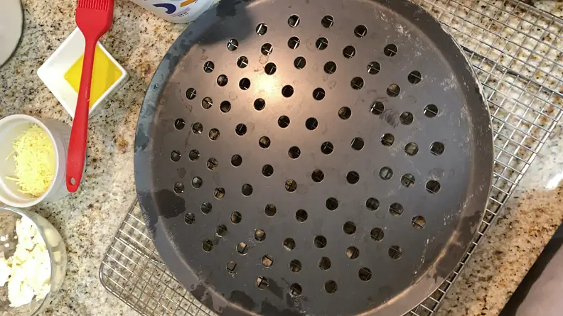 A Made In perforated pizza steel is on a cooling rack