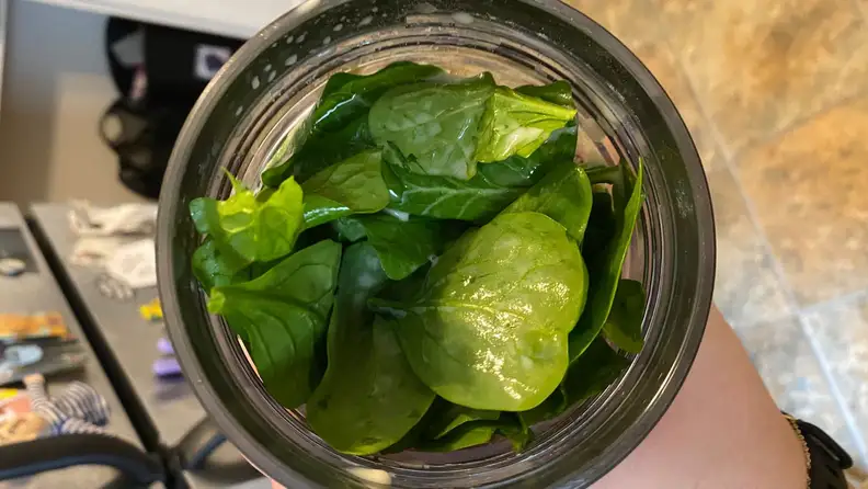 Blender cup filled with spinach shot from above