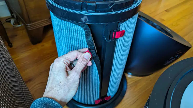 A hand pulls at a strap on the Dyson air purifier’s HEPA filter.