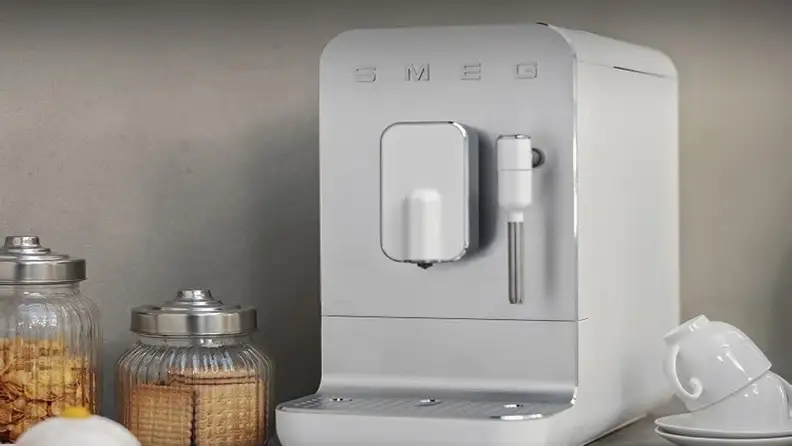 White Smeg espresso machine beside glass jars and stacked cups