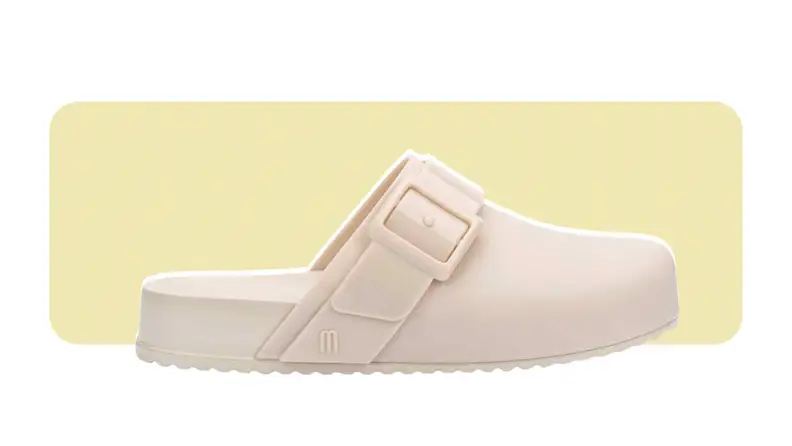 A flat clog with a strap and buckle, all made from PVC.