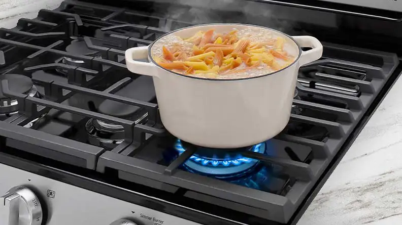 Some pasta being prepared on a pot on the oven top.