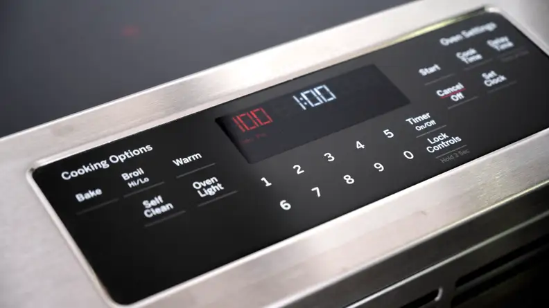 The totally flat control panel bordered by stainless steel on a GE electric range.