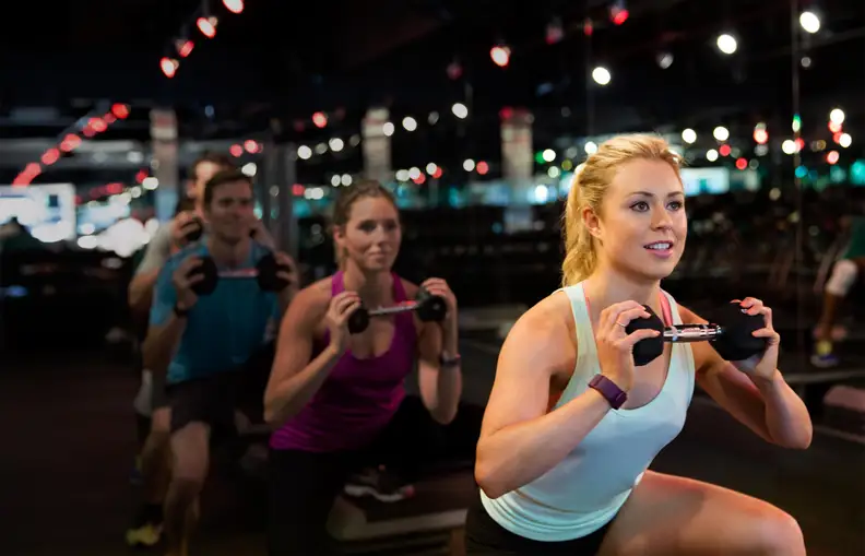 People in a workout class wearing Fitbit trackers