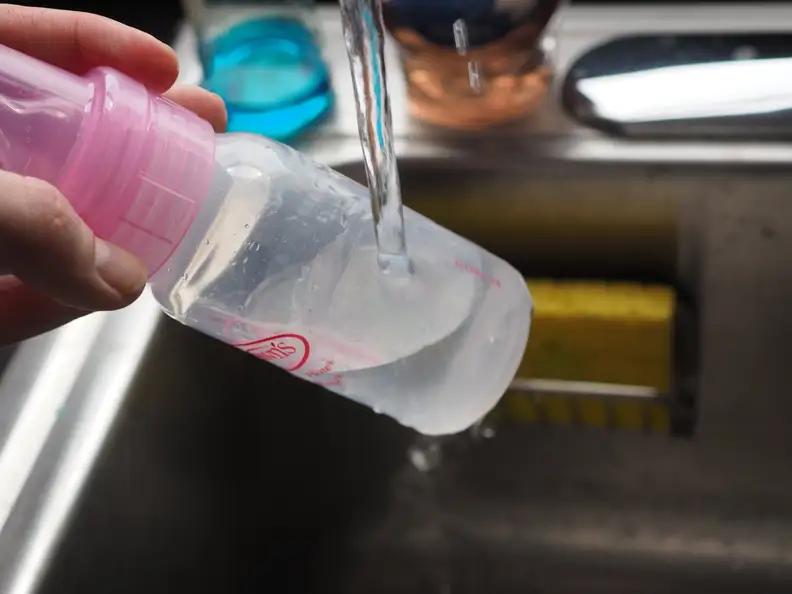 A bottle being warmed manually with hot tap water.