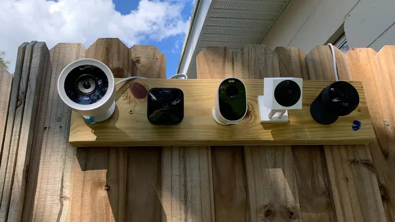 Five security cameras mounted on a wooden fence