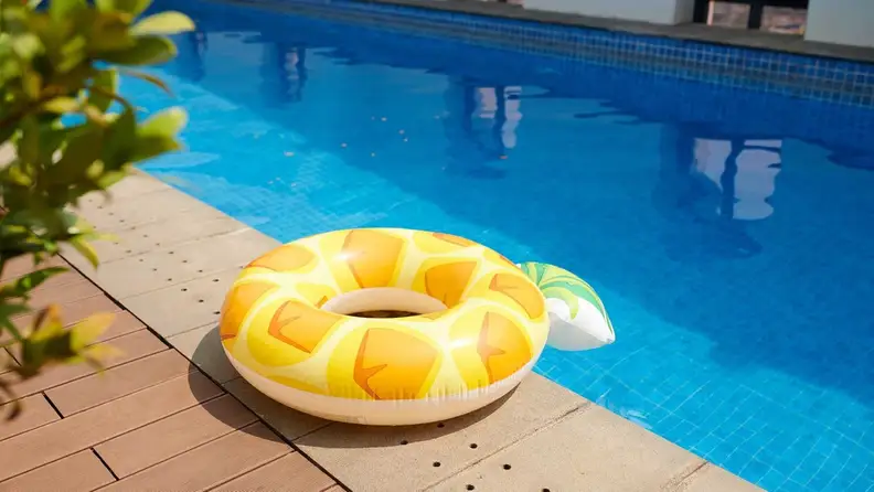 Inflatable pineapple pool float resting on deck beside pool