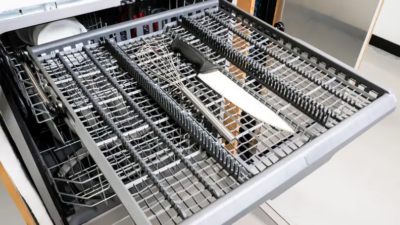A close-up of the GE GDF630PSMSS dishwasher's third rack, with a knife and some larger utensils loaded in for scale.