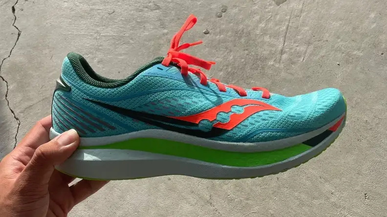 Hand holding Saucony Endorphin Speed running shoe in Spring / Future colorway.