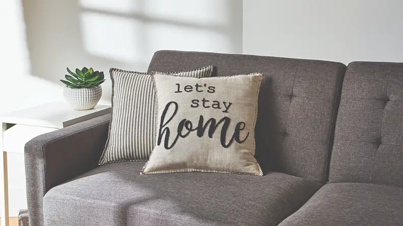 A couple of throw pillows have been placed on a couch. One reads, 