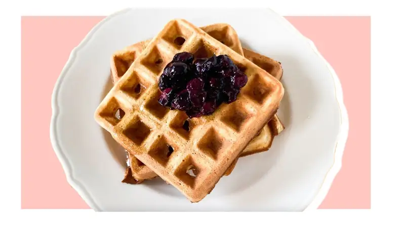 Stack of waffles with blueberry jam on top.