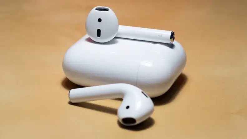 Apple AirPods on a table with a charging case.