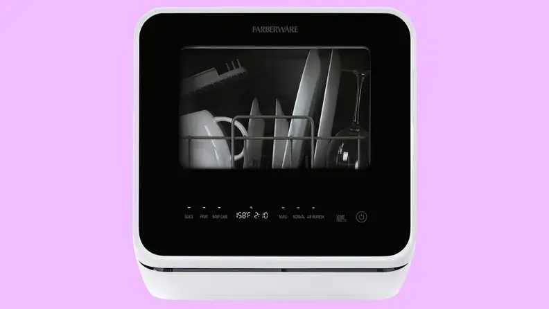The Farberware countertop dishwasher floating in a purple void. You can see some dishes stored inside it through its translucent front door.
