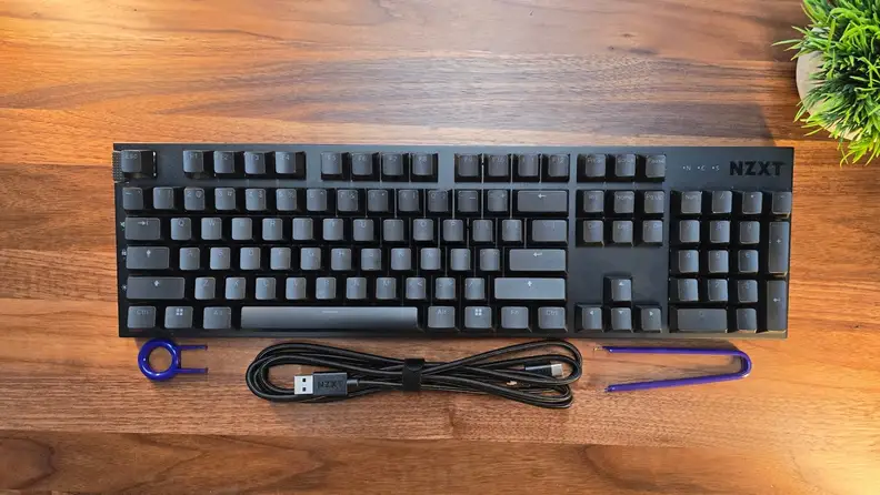 The NZXT Function 2 keyboard next to a USB cord on a wood desk.